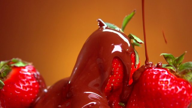 Strawberry in chocolate. Melted chocolate pouring on fresh ripe strawberries