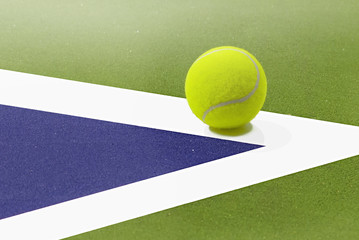  tennis ball placed on white border line inside of tenis court