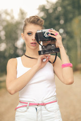 Hipster girl in shorts and a t-shirt with a vintage camera. modern hipster girl photographed using vintage camera. Outdoors lifestyle