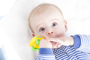 Baby with blue eyes playing with a toy