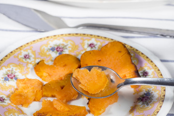 Taking a spoon of roasted sweet potato from a ceramic dish