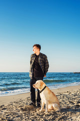young caucasian male playing with labrador on beach during sunri