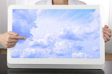 Hands holding tablet PC with sky in screen. Cloud computing concept