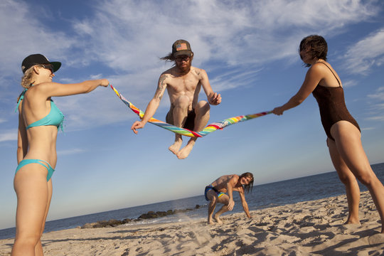 Friends playing jumping rope on the beach