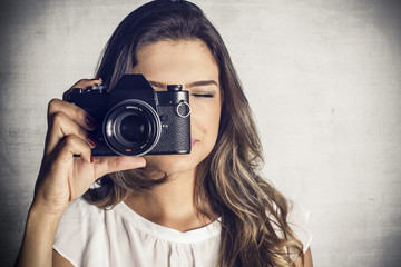 Beautiful girl taking picture with a vintage reflex camera