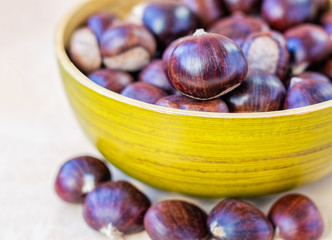 Front view of green bamboo bowl of fresh chestnuts.