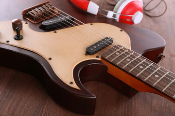 Fototapeta na wymiar Electric guitar with headphones on wooden table close up