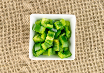Green pepper pieces on rustic hessian background