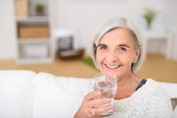 glückliche seniorin hält ein glas wasser in der hand