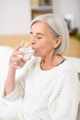 Obraz na płótnie Canvas seniorin trinkt ein glas wasser mit geschlossenen augen