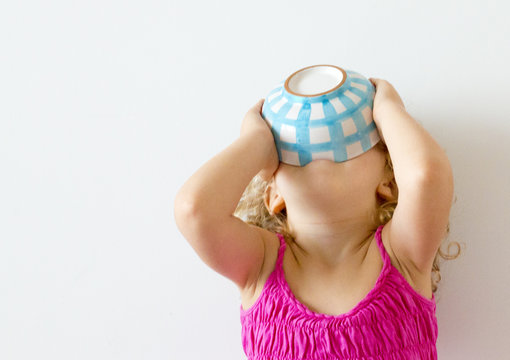 Girl with head tipped back emptying the contents of a bowl into her mouth