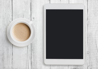Tablet pc on white table desk with coffee cup