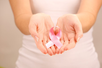 Female hands holding pink ribbon sign, closeup