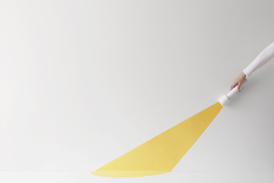 Hand holding a flashlight with a conceptual light beam