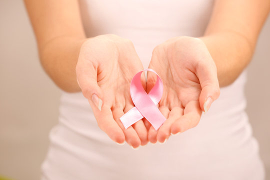 Female Hands Holding Pink Ribbon Sign, Closeup