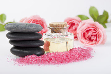 Fototapeta na wymiar Basalt stones , cosmetic oil , aromatic bath salt and rose.