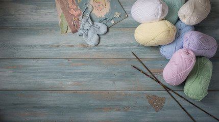 Needles, Assorted Yarn, and Booties On Faded Blue Wooden Backgro