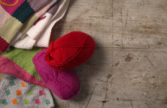 Balls of Yarn Next to Knitted Fabric on Wooden Background