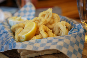 Calamari and lemon in a straw basket with paper