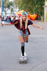 Obraz premium Young woman with skating board on the road