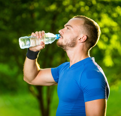 Athletic mature man drinking water from a bottle