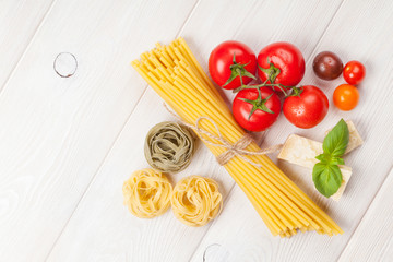 Pasta, tomatoes, basil on wooden table