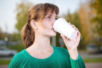 Happy young student girl drinking take away coffee.