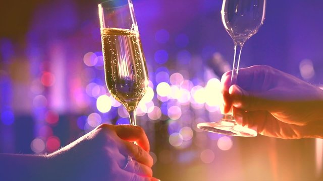 Two glasses with sparkling champagne over holiday blinking background