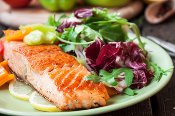 Fried salmon with vegetables on a wooden table