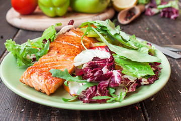 Fried salmon with vegetables on a wooden table