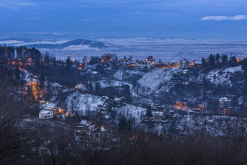 Picturesque twilight winter cityscape on the hills surrounding the city of Brasov, Romania.