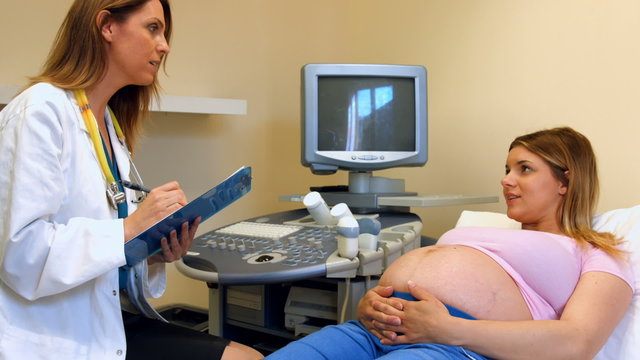 Doctor taking down notes from a pregnant patient