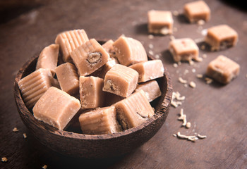 Caramel bonbons with almonds in wooden bowl,selective focus