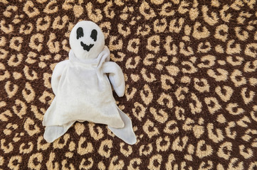 cute ghost doll on brown fabric background