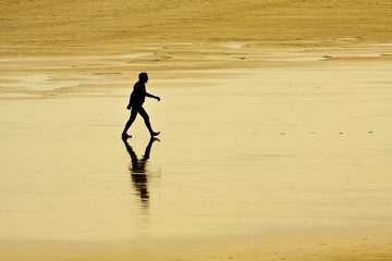 Fototapeta na wymiar Anciano paseando por la orilla de la playa 