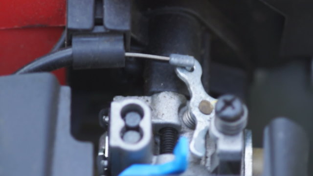 Engaging the throttle and revving the small engine of a weed trimmer and making a lot of noise.