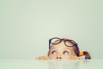 cute little girl hiding behind the table