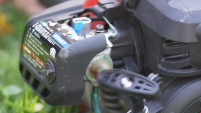 Engaging the throttle and revving the small engine of a weed trimmer and making a lot of noise.
