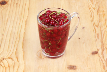 red currants in glass, isolated on wood background