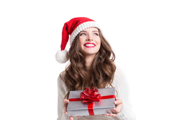 Young happy woman in santa hat looking sideways showing Christmas present.