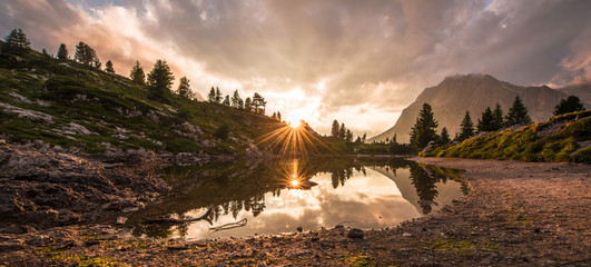 Fascinating reflections of the Dolomites mountains in lake Limedes at Sunset. Vivid and bright colors of the dramatic evening.