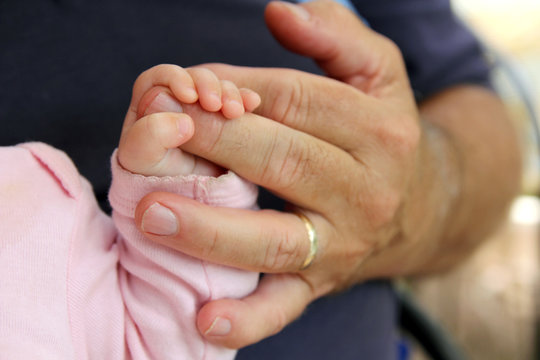 Newborn Baby Girl Holding Grandpa's Hand