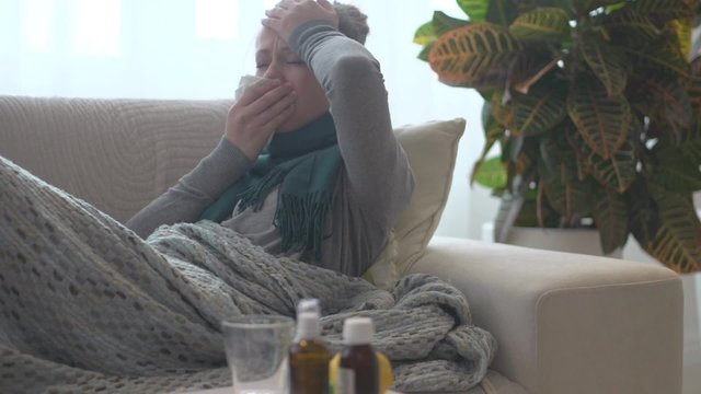 Sick woman lying on her sofa at home. Flu
