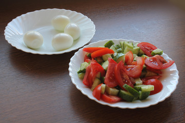 Still life. Salad with tomatoes and cucumbers on the dish, and eggs on the dish.