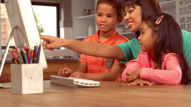 Smiling Hispanic mother on computer with her children
