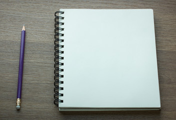 blank spiral notebook and pencil on dark wood background