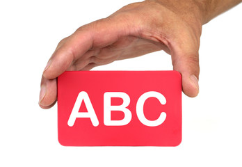 Hand holding and showing a red card with " ABC " text