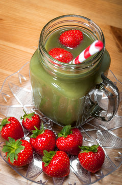 Healthy juice made out of green vegetables and fruits and some raw strawberries, the image promotes a healthy diet, lifestyle and detox