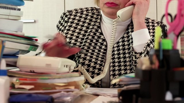 Blond business woman  talking on phone, writing down information