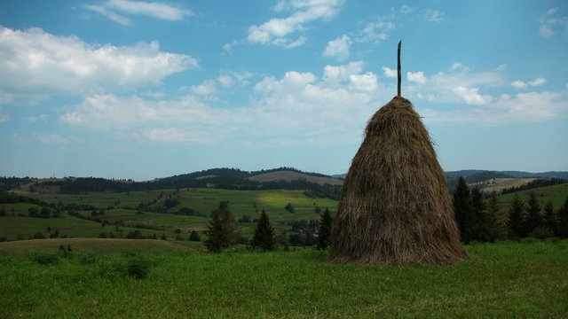 4K Timelapse of clouds and haystack on green field
